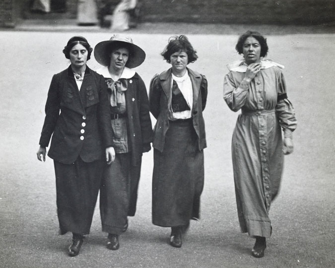 Surveillance photograph of four suffragette prisoners exercising in the yard of Holloway jail. The prisoners are identified on the reverse of the photo as Margaret Scott, Jane Short, May McFarlane & Olive Hockin. The image was taken by an undercover photographer on orders from the Home Office.
