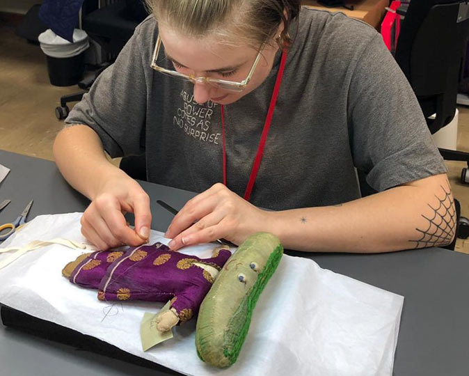 Conservation student Echo Godfrey-Simson stitches a vegetable doll, Lord Cucumber.