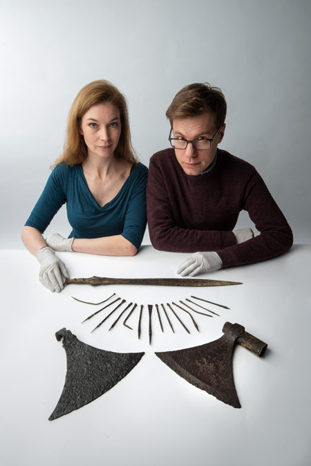 Two museum of London curators sit with a selection of objects on display in the Secret Rivers exhibition.
