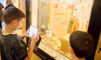 A child looks into a display case and uses their phone during a supplementary school session.