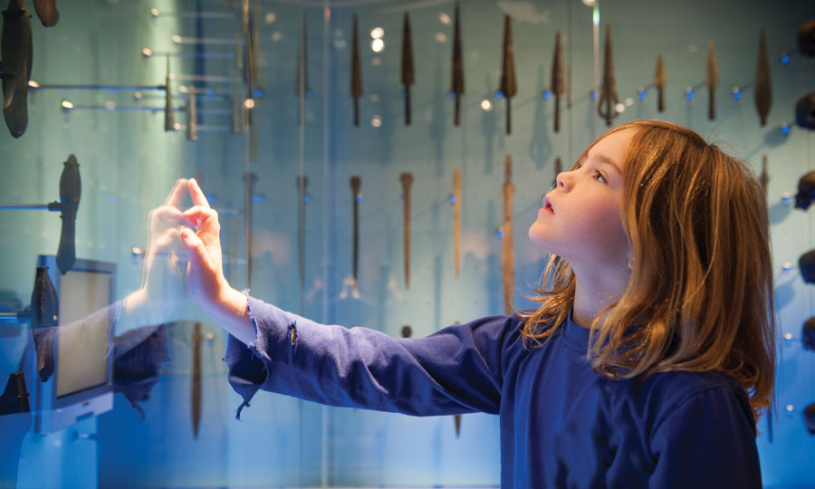 girl looking at blue display, with her hand on the glass
