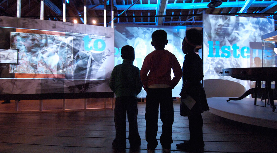 Primary pupils stand in front of a display about slavery on a visit to the  Museum of London Docklands