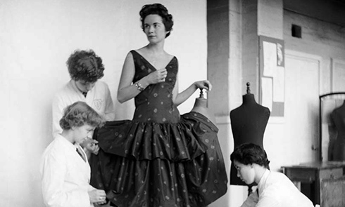Three female tailors measuring up a dress on a woman