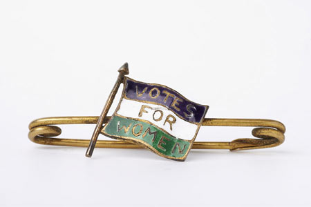 Suffragette bar brooch with gilt metal fastening and central decoration of a purple white and green enamel flag marked 'Votes for Women'.