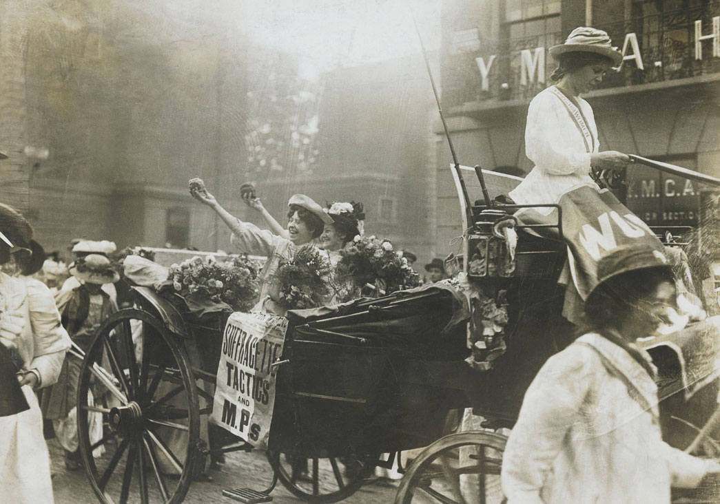 Mary Leigh and Edith New, the first suffragette window smashers, after their release from Holloway prison, 22nd August 1908. Mary Leigh and Edith New had both given up their teaching careers to become involved in the militant suffragette campaign. On 30 June 1908 they carried out the first window-smashing attack when they broke windows at 10 Downing Street, the official residence of the British Prime Minister. On their release from prison after serving two months they were greeted by a delegation of suffragettes that included Christabel Pankhurst. Presented with purple, white and green bouquets they were conducted to a waiting carriage. Here they can be seen in the carriage holding aloft loaves of bread smuggled out of the prison.