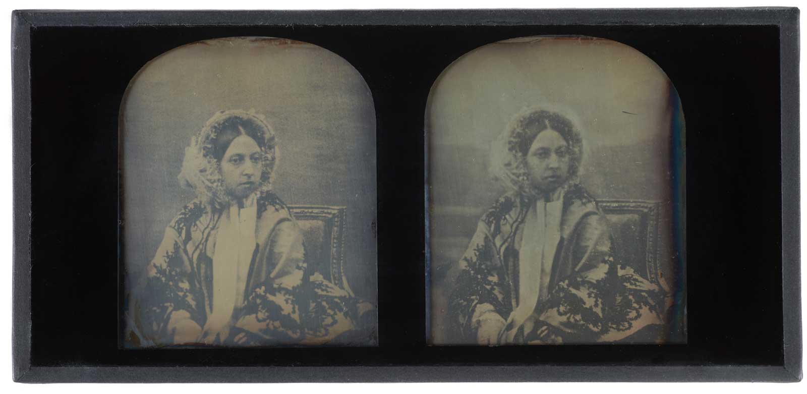 Hand-tinted stereoscopic daguerreotype of Queen Victoria, c. 1850, by Antoine Claudet.  Bookshaped, expanding case of dark blue leather. Decorated with gilt. Brass clasp. Opens to reveal two daguerreotypes and pair of binoculars. Case lined with purple velvet. Leather spine broken. One picture speckled with black.