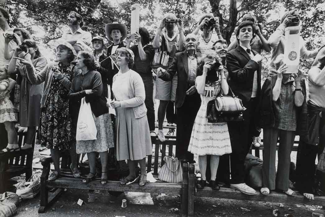 Photograph of the onlooking crowd stood on benches watching events on the wedding day of Prince Charles and Lady Diana Spencer, July 29th 1981.