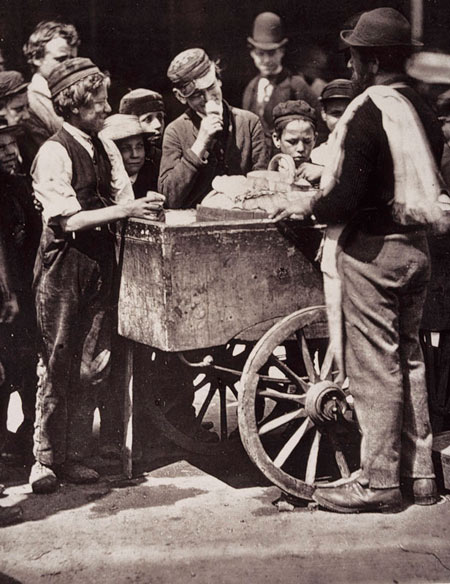 This photograph was one in a series of social documentary photographs taken by John Thomson and published in Street Life in London. Here Thomson shows customers gathered round the barrow of an ice cream seller. By the 1870s London’s ice cream and flavoured ice trade was exclusively in the hands of the Italian community who lived in Clerkenwell and Saffron Hill.  
