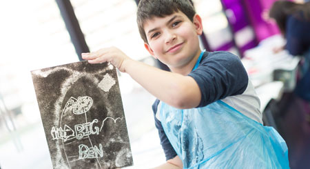 A school student holds up a piece of work created in a facilitated art session at the museum.