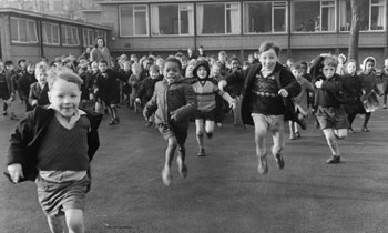 Children running across the school playground towards photographer Henry Grant. The school was the Highbury Quadrant Infants School in Islington. (c) Henry Grant Collection / Museum of London. 