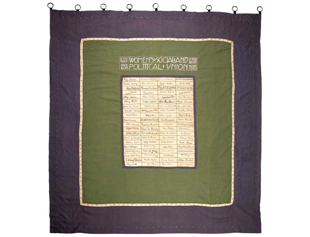 Suffragette banner composed of 80 rectangular pieces of linen sewn together and bordered by green and purple panels. The 80 pieces of linen are embroidered in purple cotton with the signatures of eighty Suffragette hunger-strikers who, by 1910, had 'faced death without flinching'. Along the top is embroidered 'Women's Social and Political Union' in Scottish art nouveau style along with the names of the suffragette leaders Emmeline and Christabel Pankhurst and Annie Kenney. The banner was first carried in the 'From Prison to Citizenship' procession in June 1910 to symbolise the spirit of comradeship that gave suffragette prisoners the strength and courage to endure hunger strike and force feeding. 