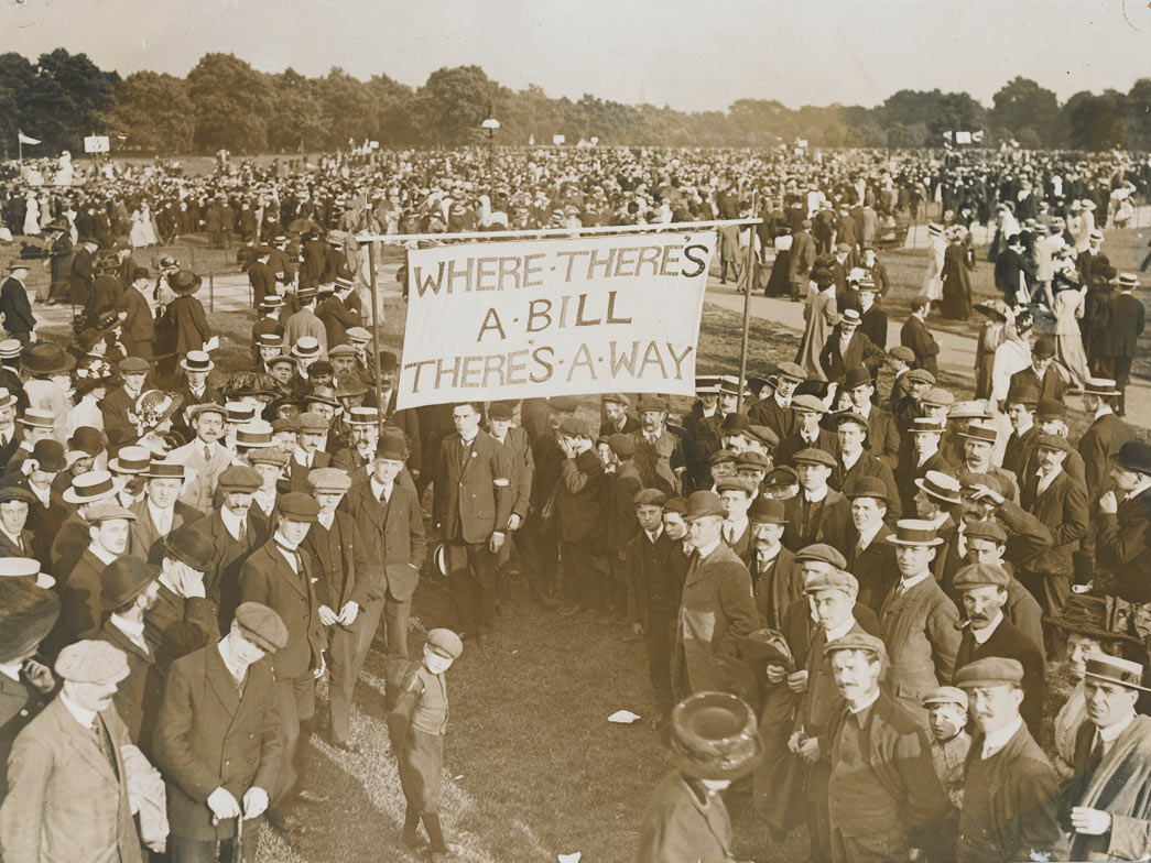 A WSPU rally in Hyde Park in support of the Conciliation Bill, 23 July 1910. This group of male supporters is making its way to one of the four platforms for men's groups. If the Conciliation Bill had been passed by Parliament it would have given the vote to women who occupied premises for which they were responsible. Single women would have been the greatest beneficiaries of such a Bill.

