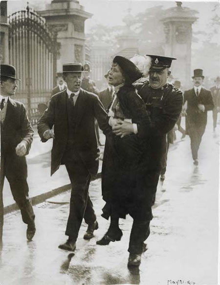 Emmeline Pankhurst being arrested while trying to present a petition to the King at Buckingham Palace, 21 May 1914. As she was being carried past a group of reporters Emmeline called out 'Arrested at the gates of the Palace. Tell the King'. Having been released from prison in March under the terms of the Cat and Mouse Act Emmeline had failed to return to Holloway at the end of the month. Arrested at Buckingham Palace she was driven straight back to Holloway to continue her sentence. The arresting officer, Chief Inspector Rolfe, seen here carrying Emmeline away from the demonstration had been ordered to arrest Emmeline by the Home Office. He died two weeks later on 26th July of blood poisoning caused by an injury to his elbow following a fall whilst on duty at Shrewsbury. Emmeline's attempt to petition the King represented a change of tactics by the suffragette leader. During 1914 she decided to bypass government ministers and deal directly with 'the Throne'. She had seen that such an appeal by Irish republicans had resulted in the King calling an Irish conference but Emmeline's attempt to engage similar royal interest in the suffragette campaign ultimately failed.

