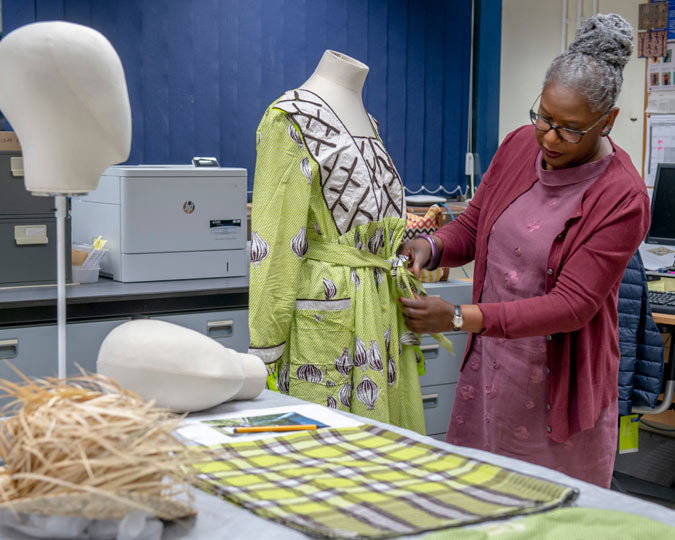 Iyamide Thomas inspects a dress before it goes on display.