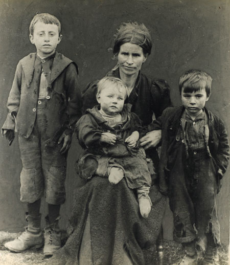 A poverty stricken East End family, circa 1900. A mother with her three children, all dressed in rags.