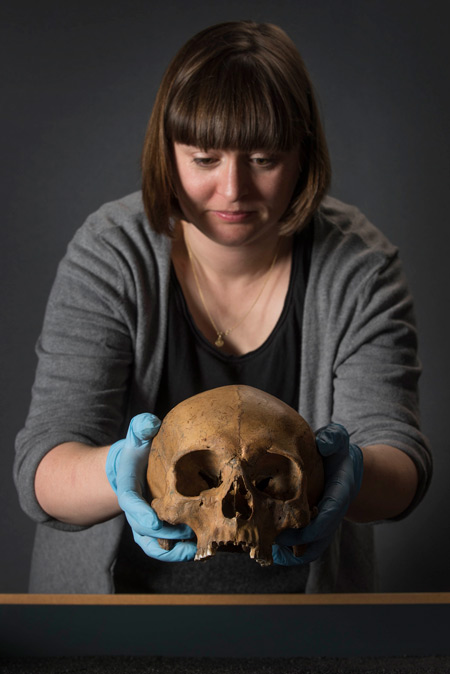 An osteologist at the Museum of London holds a Roman skull.