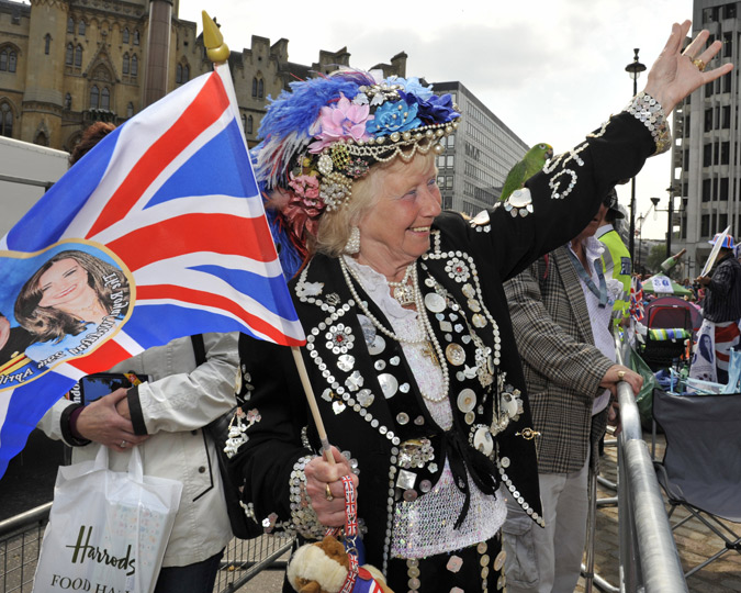 A Pearly Queen waves a flag at the passing wedding parade of William and Kate.