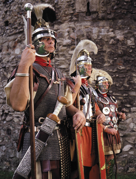 Close up of Roman soldiers, Ermin Street Guard photographed next to London Wall. Actors re-enacting a line of Roman soldiers wearing uniform, helmets and badges of office.

