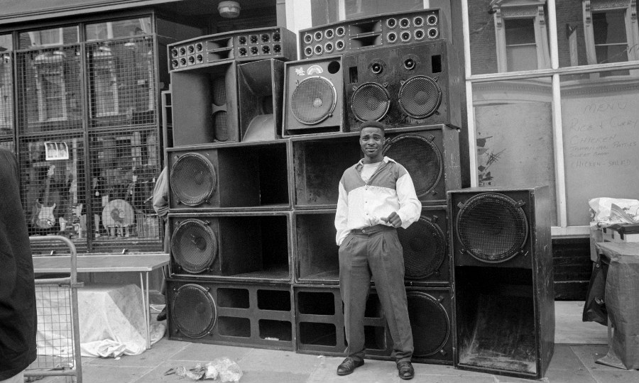 Black and white image of a man standing in front of soundsystem