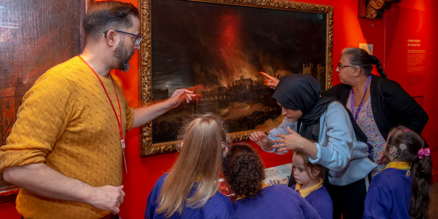 a group of primary school children and adults inspecting a painting showing the Great Fire of London