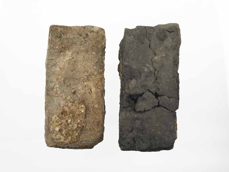 Top and bottom of a 17th century brick. One side is black and charred. It is from a shop on Pudding Lane, which had burnt down during the Great Fire in 1666. 