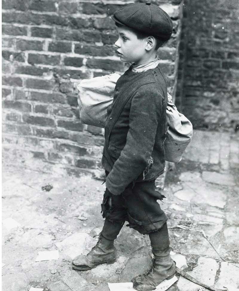 A young boy returns from the pawnbroker, a bundle of clothing under his arm in brown paper. The photo appears in an album with other prints depicting London's poor. 