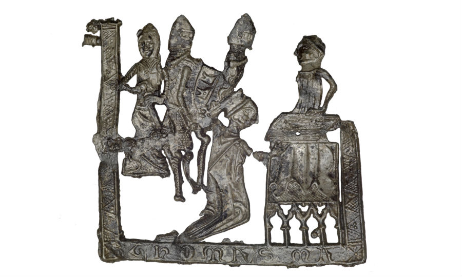 Pilgrim badge from the shrine of St Thomas Becket at Canterbury Cathedral. This badge depicts the scene of Becket’s martyrdom. An inscription at the base of the badge reads 'THOMAS MA’ (meaning ‘Thomas Martyr’). Becket is on his knees in front of an altar with four knights attacking him. Behind the altar stands the figure of Edward Grim, a clerk who tried to stop Becket’s murder. One of the knights carries a shield with two bears’ heads on it, identifying him as Reginald Fitzurse (through the visual pun on the Latin ‘ursus’, meaning ‘bear’). Fitzurse was the knight popularly believed to have struck final blow that killed Becket. An irregular line running across the badge suggests that it was made in a cracked mould.