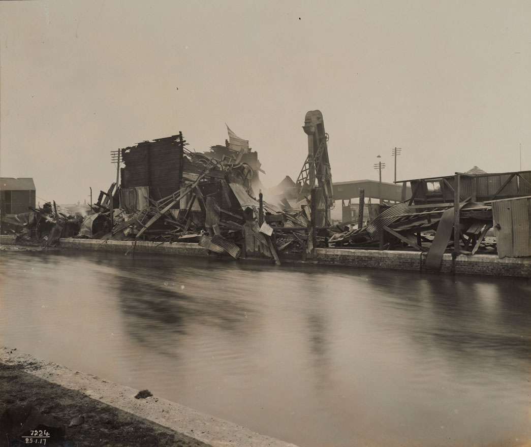 Wreckage of the Silvertown explosion. D silo was completely destroyed by fire caused by the Silvertown Explosion. It was still burning when this photograph was taken - despite having had well over 100 firefighters in attendance, the PLA Chief Police Officer reported on 8th Februrary that D silo was 