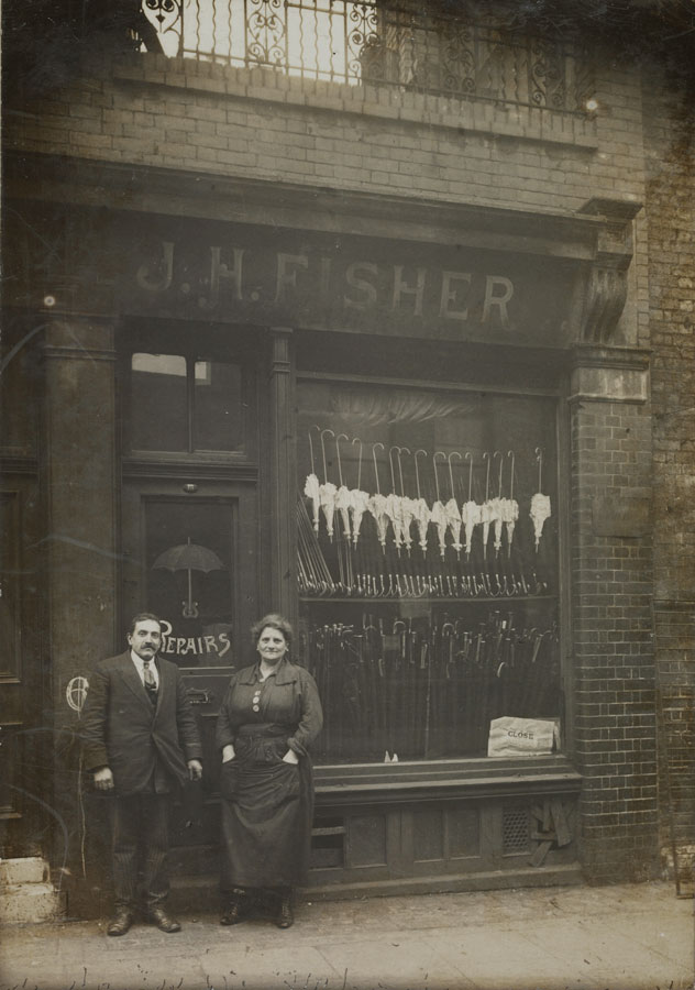sepia photograph of couple posing in front of their umbrella shop