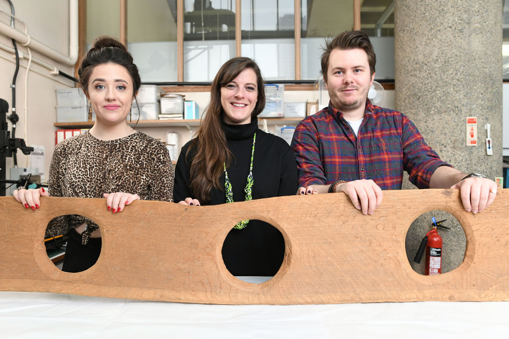 Museum of London staff hold a modern reproduction of the communal toilet seat.