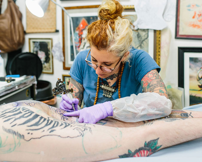Tattoo artist Claudia de Sabe at work on a client. Copyright Kate Berry.
