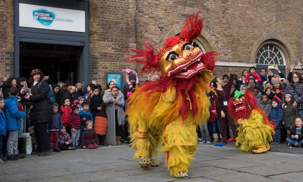 Three lion dancers in colourful costume perform outside at Chinese New Year celebrations at the Museum of London Docklands.
