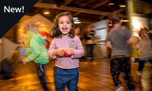 A photograph of an excited child in a museum gallery with people moving in the background.