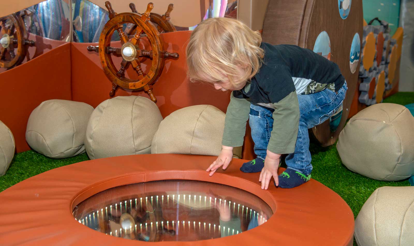A toddler enjoys a floor mirror in the baby exploratory area of the Mudlarks children's gallery. 