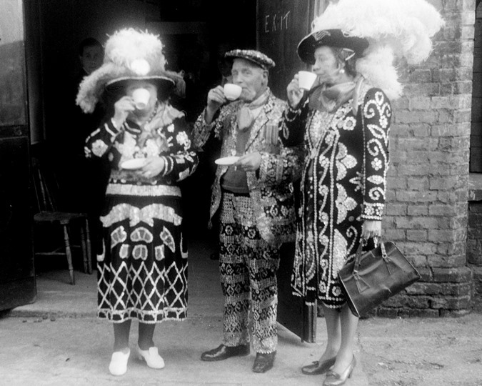 Pearly King and Queens drinking tea, 1951
Pearly King and Queens drinking a cup of tea at the annual traditional Costermongers Harvest Festival Service. (Courtesy of Henry Grant, ID no.: HG1328/20)
