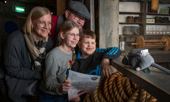 a family group looking at a stuffed toy rat in costume in the Sailortown gallery