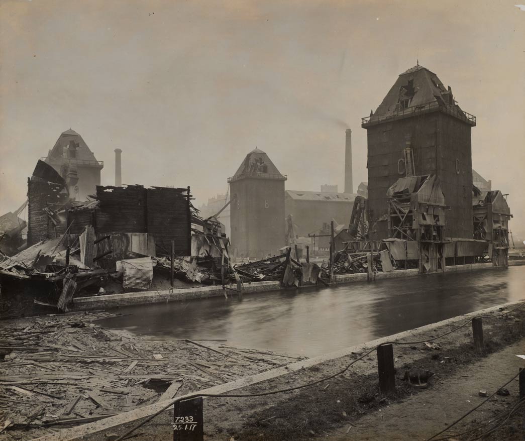 Photograph showing the damage to the bulk grain office exterior, Royal Victoria Dock, following the Silvertown explosion. Photograph taken by John H Avery on 25 January 1917.