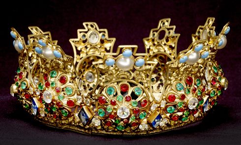 Crown made from gilt metal and set with multicoloured paste stones. There is a padded textile band around the inside. (ID no.: A23255/14)