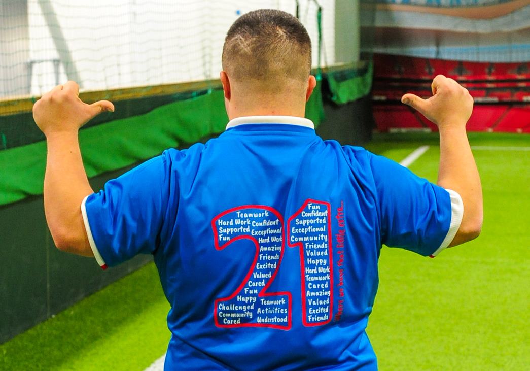 The words on back of the t-shirt are shaped to the number 21 which refers to having an extra 21st chromosome. North London United is a football project for young people born with Down syndrome. 