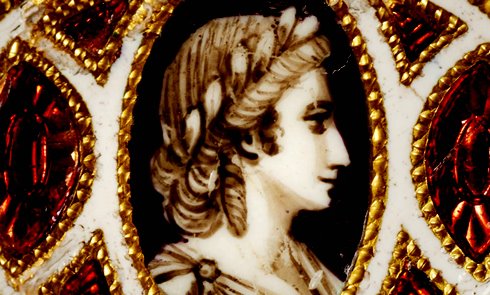 A woman depicted as a Roman laureate female, possibly a Muse, on one of a pair of miniature bracelet plaques made of gold. It is possible that the 18th century recipient of the plaques was named after the Muse and that the figure depicted is a delicate reference to the classical antecedents of her name. (ID no.: C1705)