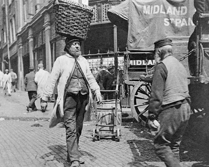 A fish porter working at Billingsgate is photographed completely unawares of the camera. Paul Martin was the first photographer to roam around the streets of London with a disguised camera taking candid pictures such as this solely for the purpose of showing 'life as it is'. (IN3044)