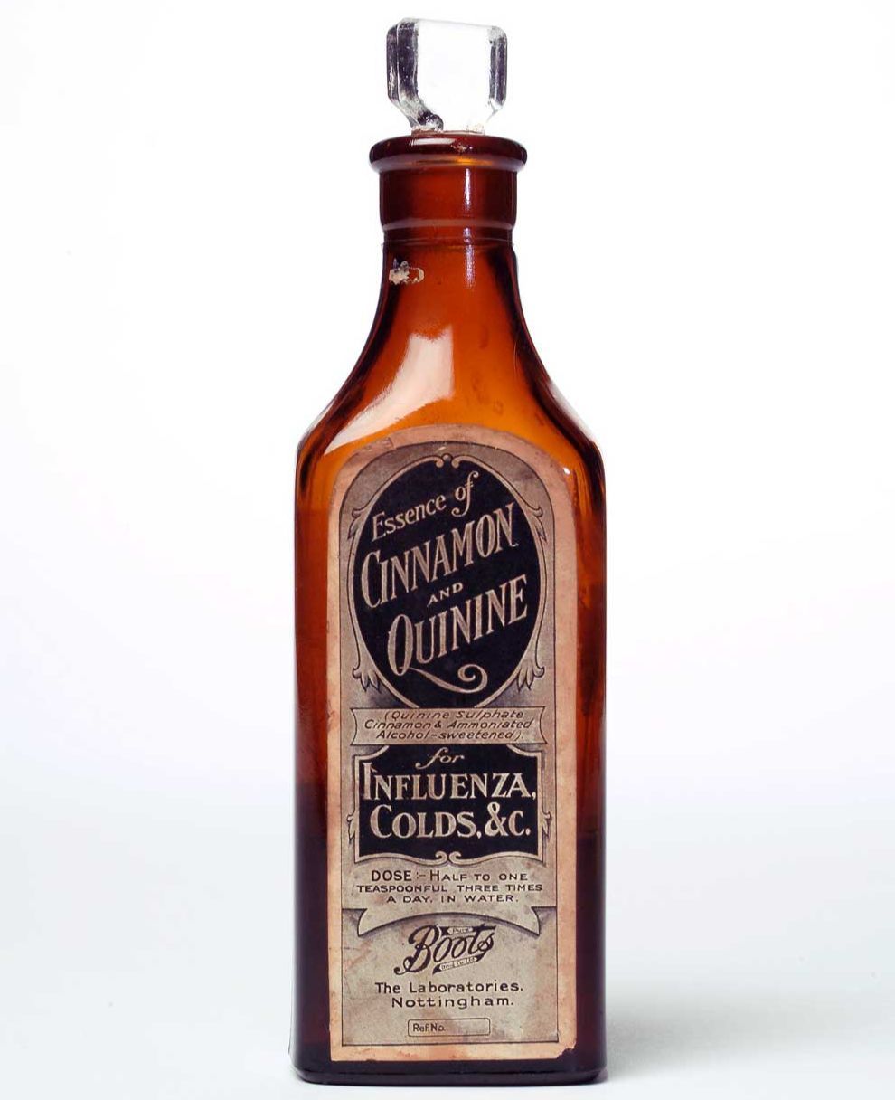 A brown glass chemist's bottle with paper labels inscribed 'Essence of Cinnamon and Quinine for Influenza and Colds'.