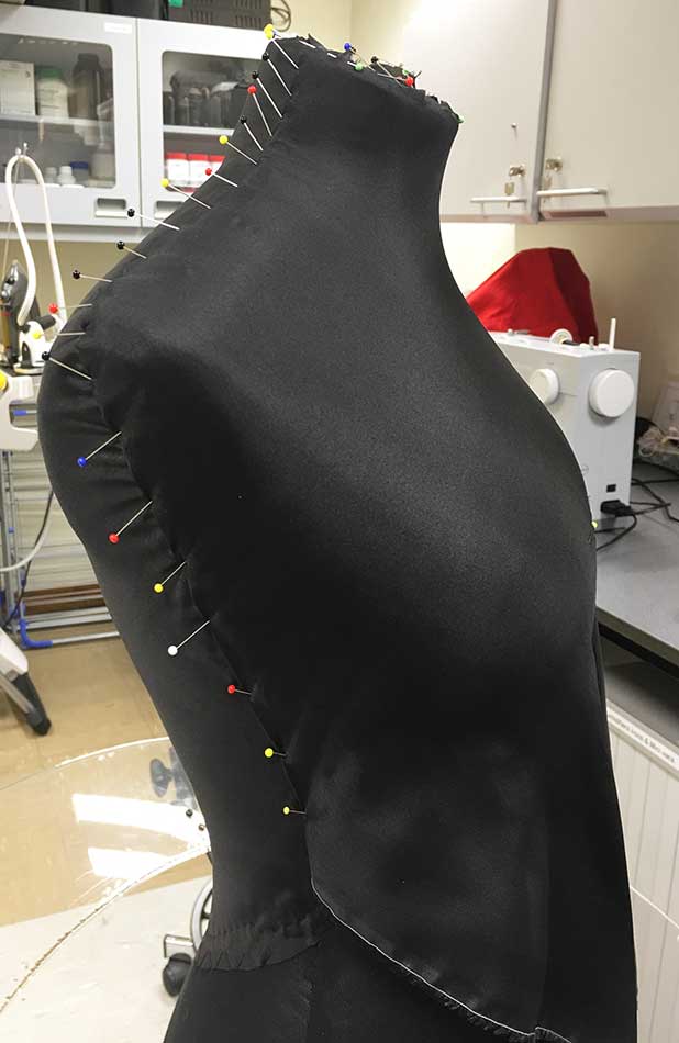 Pinning black silk Habotai display fabric to padded mannequin.