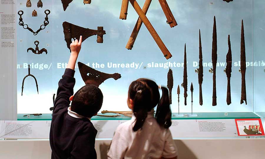 Pupils peep at a display of medieval objects during a school visit.
