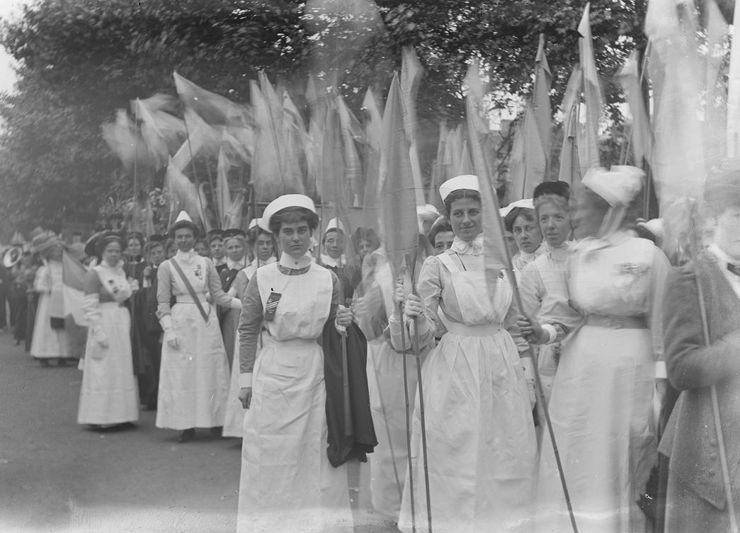 A photograph by Christina Broom, a pioneering professional photographer and is considered to be the UK's first woman press photographer. Nurses an midwives prepare to march in the Women's Coronation Procession. (ID no.: IN1346)