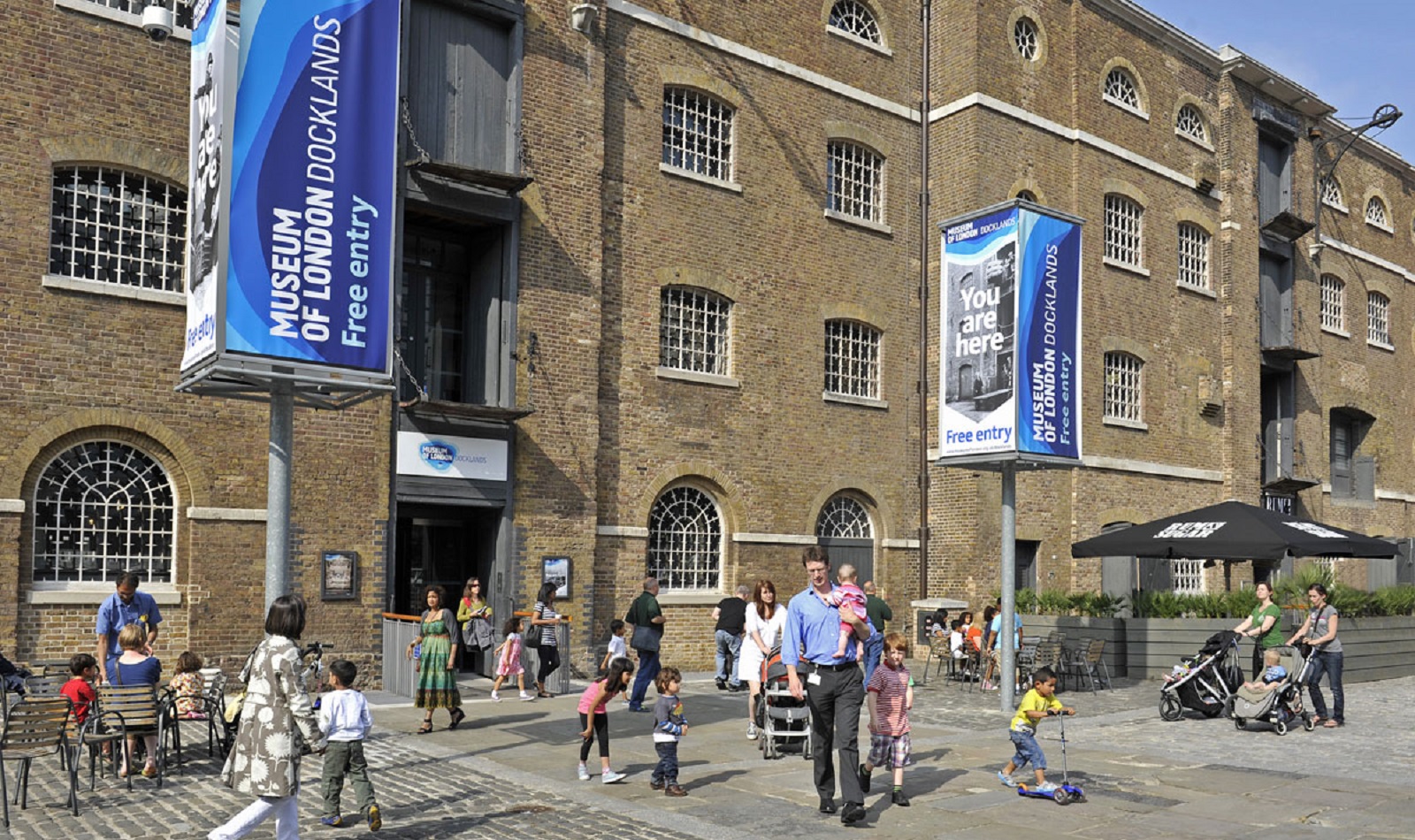 An outside view of the Museum of London Docklands with families in view.