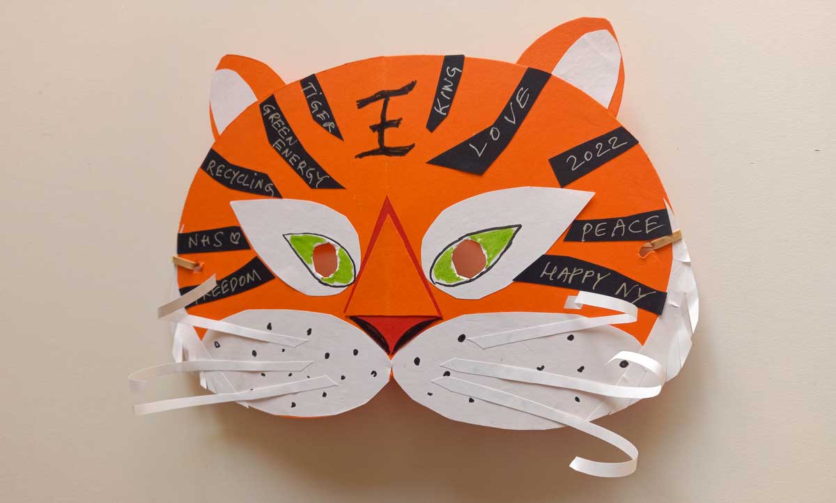 A colourful orange, white and black homemade paper mask.