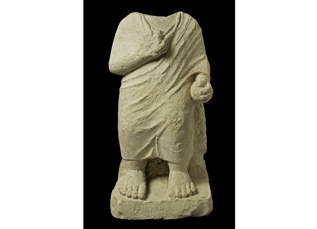 A boy holding a ball
Roman era (100-300 CE) limestone statue of a boy, now headless, wearing a toga, right arm across his breast holding a bird, left by his side holding a ball. (ID no.: 61.122) 
