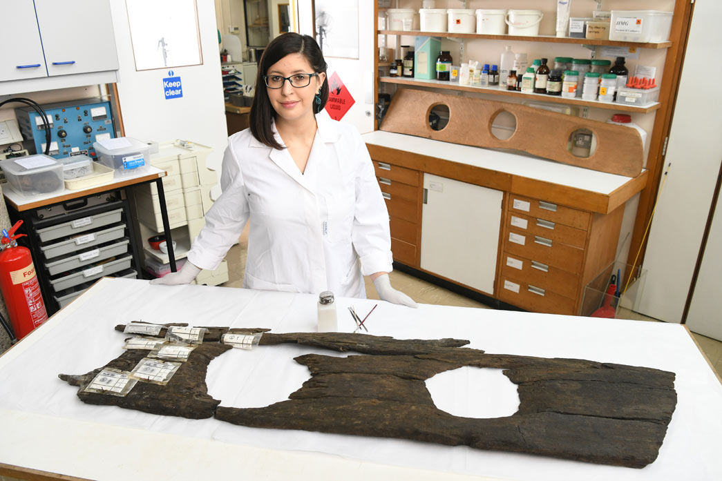 A conservator stands beside the remains of a triple toilet seat excavated from the river Thames. 