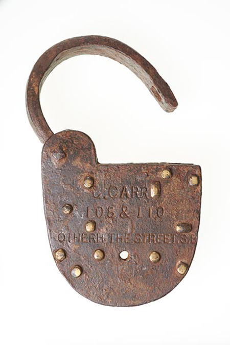 Iron barge padlock with brass pins. Impressed in the front of the lock is ' JOHN WAL' and underneath '909'. The front also has two trademarks impressed, one either side of the keyhole. On the back is impressed 'G. CARR 108 & 110 Rotherhithe Street'. Recovered from the Thames foreshore. George Carr was a barge builder and engineer who had premises on Rotherhithe Street.